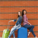 Two female friends travelling along with their travel bags